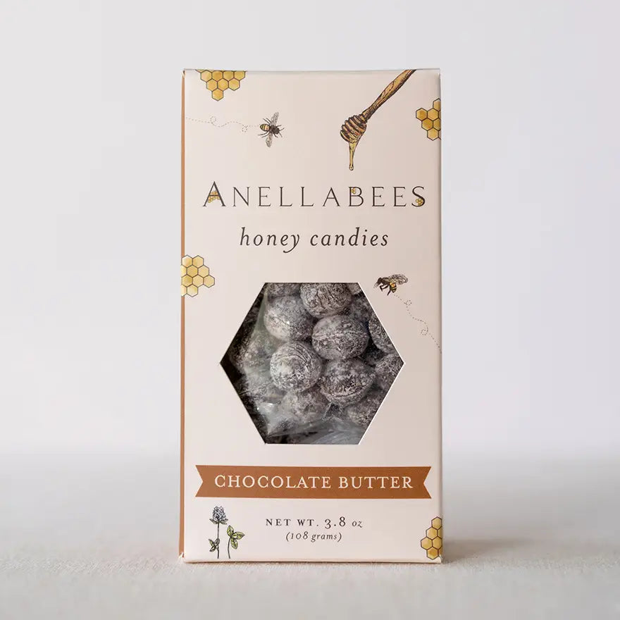 anellabees honey candies chocoalte butter in tan package with bee and honey combs randomly on the package, honeycomb shaped cut out window showing candies