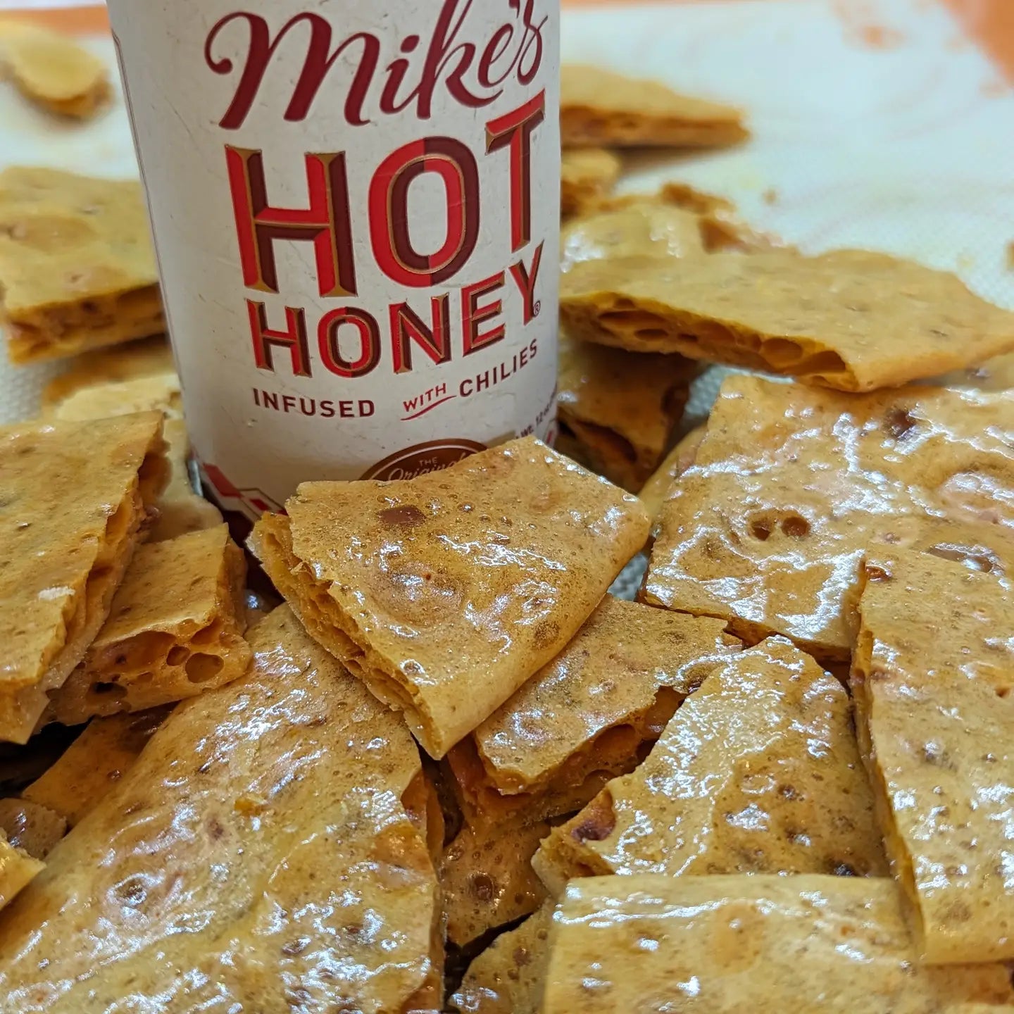 close up of crunchy brittle and part of the bottle of mike's hot honey