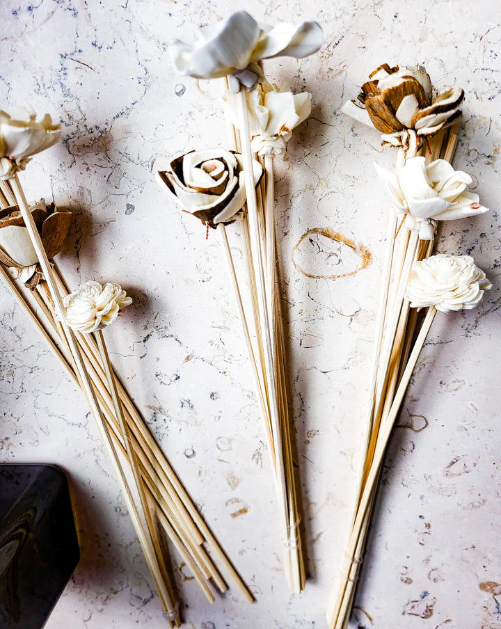 three piles of reed diffusers with roses on the top