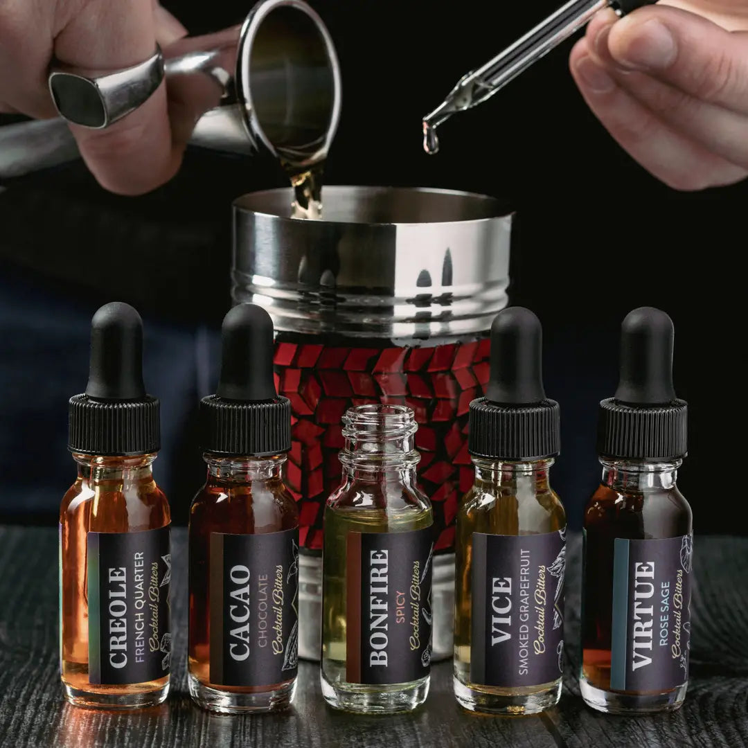 mans hands, pour beverage into drink shaker and dropping cocktail bitters in as well, five flavors of bitters across the front 