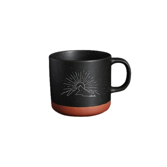 black coffee mug with a tan bottom, designed wtih a sunrising over a mountain