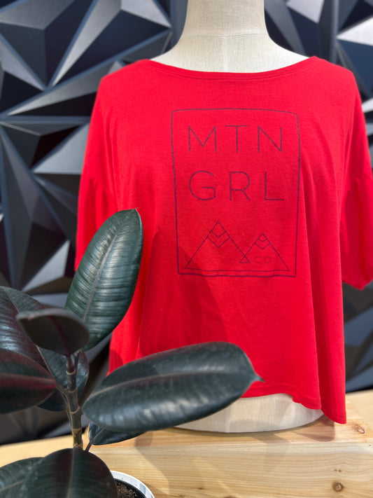 mannequin on a table, wearing red crop loose fitting tee with wide neck - rectangle MTN GRL with mountains