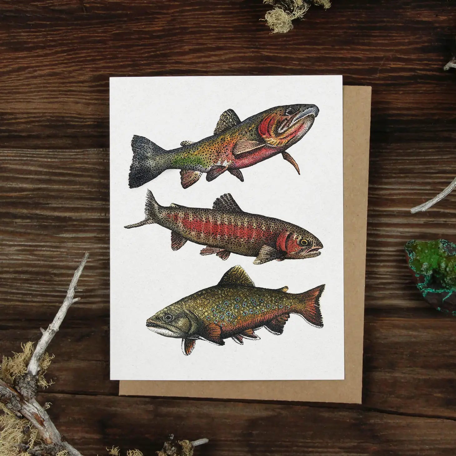 greeting card with three trout, on top of a tan envelop laying on a wood table